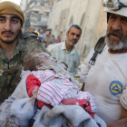 Miembros de los Cascos Blancos llevan en brazos el cuerpo de una niña sacado de las ruinas de un edificio destruido tras un bombardeo en Alepo.
