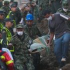 Los socorristas transportan el cuerpo de una joven que falleció por el deslizamiento de tierra.