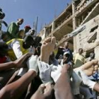 Un superviviente es sacado por una multitud de entre los escombros de un edificio de cuatro pisos