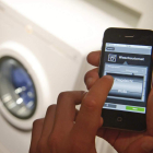 Una persona activa el programa de una lavadora a través de su teléfono móvil.