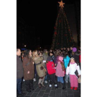 Los niños miran el gran árbol navideño al encender sus luces.