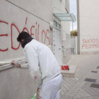 Un operario borra pintadas contra los acusados en la parroquia de Román Martínez.