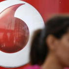 Una mujer habla por móvil frente a un anuncio de Vodafone.