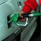 Un encargado de una gasolinera llena el depósito del vehículo de uno de sus clientes