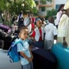 Un grupo de niños espera junto a unas maletas su evacuación de Puerto Príncipe