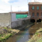El canal de agua de La Moldera pasa bajo una construcción, en las afueras de Astorga.