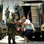 Un soldado y un miembro de seguridad intentan trasladar a un militar herido en los enfrentamientos