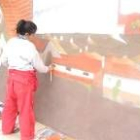 La joven artista Nonia Villa trabajando en el mural de la iglesia
