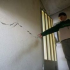 El joven muestra una de las grandes grietas que atraviesan el tabique de su vivienda en el pueblo de