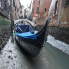 Una gondola permanece amarrada en un canal practicamente sin agua en Venecia.