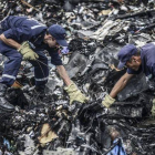 Dos agentes buscan entre los restos del vuelo MH17 de Malaysia Airlines.