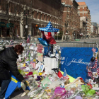 Varias personas depositan flores en recuerdo de las víctimas de la tragedia.