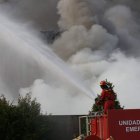 Un soldado de la UME arroja agua al interior de la planta de reciclaje, donde el fuego se apagará cuando se consuma su combustible de neumáticos