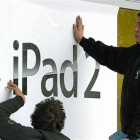 Renovación 8 Dos trabajadores cuelgan carteles del iPad 2 en Berlín.