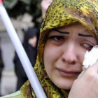 Una mujer libanesa llora mientras sostiene una bandera palestina.