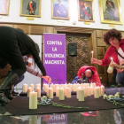 Asistentes al acto de homenaje a las víctimas de la violencia machista que se ha celebrado hoy en el consistorio zaragozano, encienden unas velas.