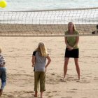 Una madre juega con sus hijos en una playa .