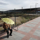 Un hombre se protege del sol y el calor con un paraguas sentado en un banco de la ciudad.