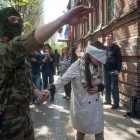 Un hombre con pasamontañas y ropa militar conduce a la activista y periodista ucraniana Imra Krat, retenida por manifestantes prorrusos