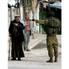 Un soldado judío indica a un anciano palestino la dirección prohibida