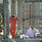 Un recluso de Guantánamo, escoltado por dos guardias en el penal, junto a otros dos presos en sus celdas, el 15 de marzo del 2002.