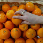 Una persona coge una naranja en un supermercado.