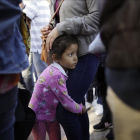 Una niña mexicana con su madre espera con otros inmigrantes en la frontera la respuesta a la solicitud de asilo político en EEUU. /