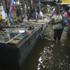 Tailandeses en un mercado anegado por las inundaciones.
