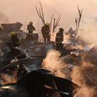 Un grupo de bomberos trabaja entre los escombros de varias casas devoradas por las llamas en Valparaiso.