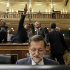 Mariano Rajoy, en su escaño, mientras, detrás, varios diputados observan la gotera del Congreso.