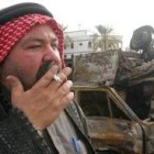 Un iraquí pasa ante los restos calcinados de un vehículo norteamericano destrozado en un atentado
