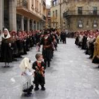Fieles vestidos de maragatos desfilan por Astorga, acompañando a la Cruz Dorada