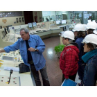 Un operario de la eléctrica muestra un cuadro de control a un grupo de jóvenes estudiantes.