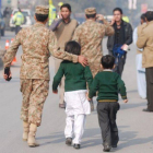 Un soldado paquistaní escolta a dos niños rescatados de la escuela que ha sufrido el ataque en Peshawar.