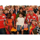 Los dos pilotos de Ferrari, Massa y Alonso, posan con varios niños en un evento de Ferrari.