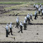 La policía vestida con trajes de seguridad nuclear busca víctimas cerca de Fukushima.