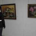 Una joven contempla algunos de los cuadros de Ascensión Alonso expuestos en la biblioteca