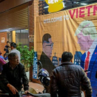 Ciudadanos de Hanói pasan ante un cartel con las imágenes de Kim y Trump horas antes de su encuentro.