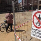 Una mujer se apea de la bicicleta para atravesar las obras de la plaza Mayor.