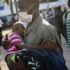 Un hombre carga a un niño en el Hospital San Nicolás de Saint Marc, protegido contra el cólera