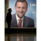 Un simpatizante del PP observa un cartel del líder popular, Rajoy