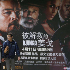 Dos personas pasan frente a un cartel de la última película de Tarantino.