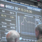 Dos inversores observan una pantalla con la evolución del Ibex 35 en la Bolsa de Madrid.