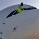 Un trabajador limpìa las ventanillas de la cabina de un avión antes de que despegue