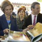 La reina ojea uno de los libros que se venden en la Feria del Libro.