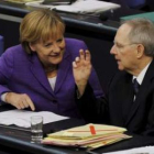 Merkel conversa con el ministro de Finanzas durante una sesión en el Parlamento.