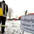 Un bombero alemán traslada una bombona con desinfectante junto a un cartel sobre la gripe aviar