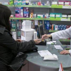 Una usuaria abona el euro por receta en una farmacia de Barcelona.