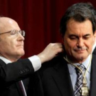 El presidente saliente, José Montilla, coloca a Mas la medalla que le acredita como mandatario.