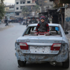 Un niño sirio sentado sobre un coche dañado por las explosiones del este de Ghouta.